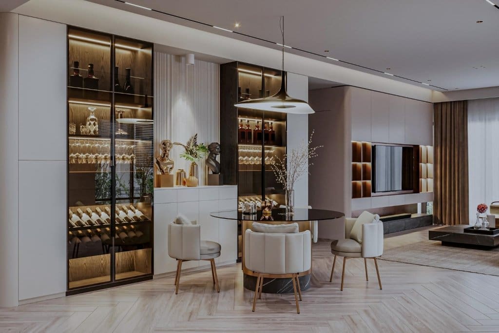A contemporary dining area showcases cream chairs around a dark glass table beneath a statement pendant light, near illuminated liquor storage.